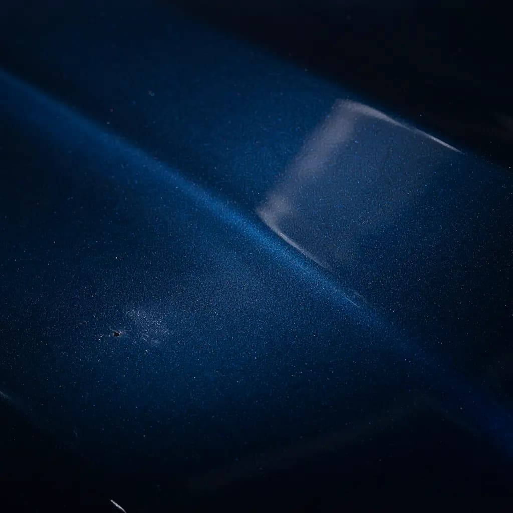 New car paint under inspection lighting showing transport film residue and fallout contamination that must be removed before ceramic coating at Tint Bros Adelaide